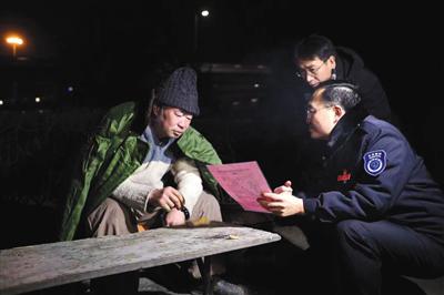 2018年12月31日,四惠桥附近的绿化带中,向阳区民政局的做事人员给漂泊乞讨人员送棉衣,并讲解援助政策。 新京报记者 彭子洋 摄