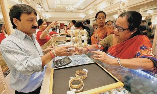 印度加尔各答一家金店的店员向消费者展示金饰。路透社