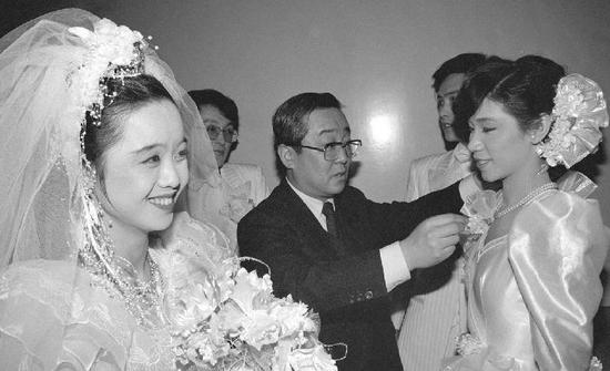 1988年2月6日,特地从事婚礼照相的中日合资照相馆总经理高崎纪一郎(中)在北京民族文化宫为参与集体婚礼的新娘整理服装。