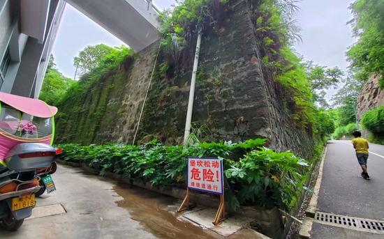 6月22日，新晃一中通往跑道的路旁设置了“堡坎松动危险！请绕道通行”的危险提示牌。 新京报记者 李云蝶 摄