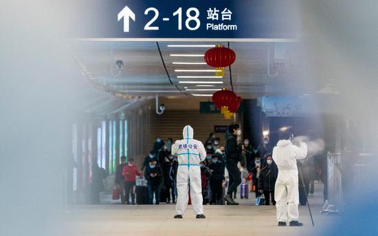 汉口火车站出站口,旅客们从各地返回,警务人员身穿防护服就位.