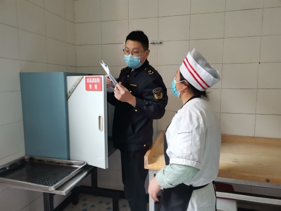 圖為胡用軍正在學校食堂開展食品安全檢查(受訪者供圖)