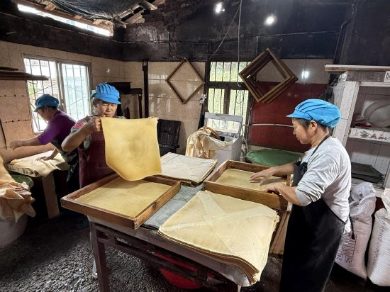 图为作坊工人正在从压制模具中取出压制好的半成品观音豆腐干