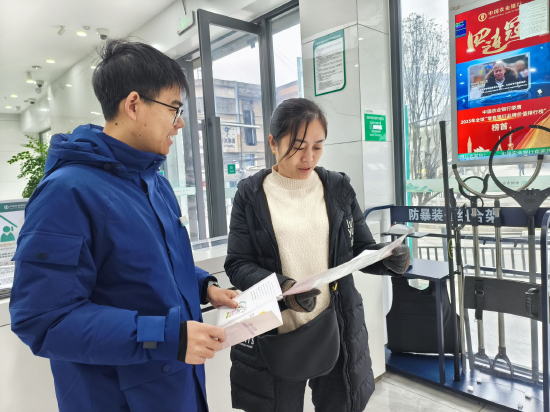 图为农行达州万源市白沙支行客户经理向到店顾客宣传金融新政策