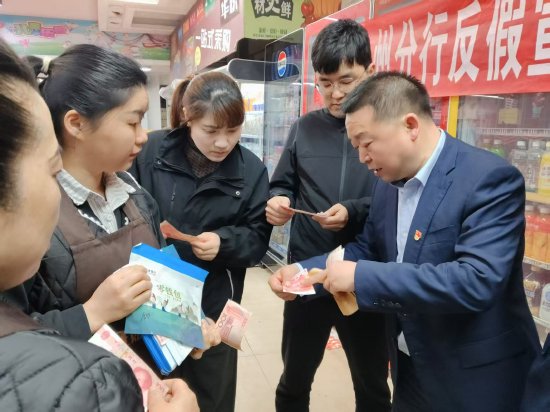 图为达州分行现金中心支部党员在石桥镇一超市里向群众普及反假币知识