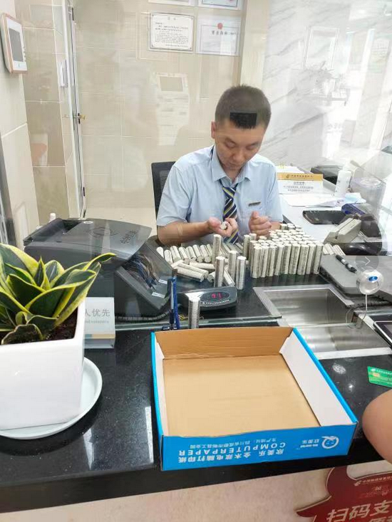 邮储银行成白路支行工作人员正在为客户办理硬币兑换业务