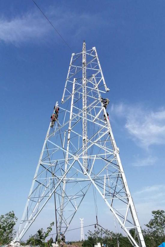 市迎祥镇,电力工人在永安站至金鹅站220千伏线路工程现场进行铁塔组立