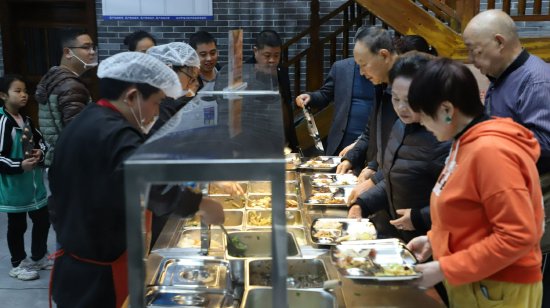 社区居民在食堂内有序排队打饭，工作人员热情服务