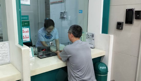 图为刘先生将业务资料递交给农行服务人员