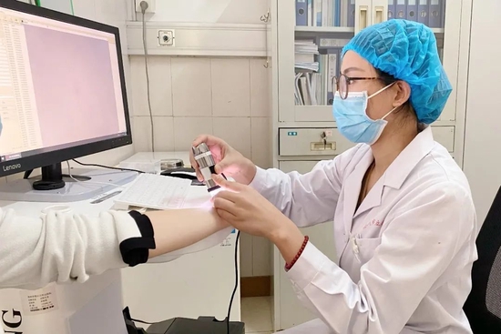 皮肤科医生使用皮肤镜检测仪为患者诊断