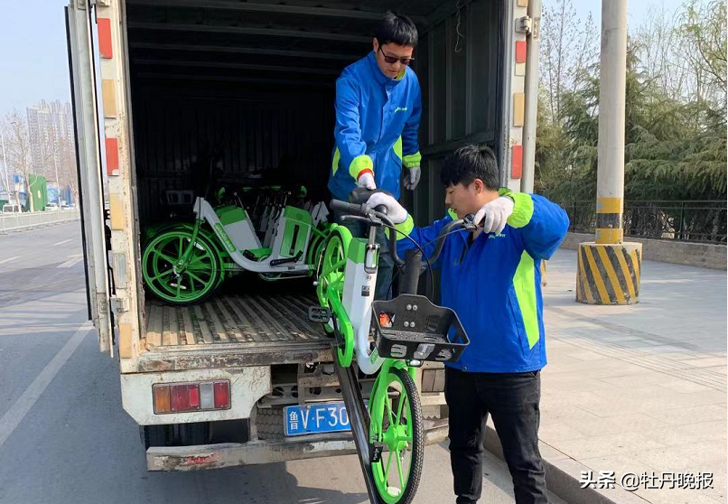 助力单车站点附近,两位永安行的工作人员正在向停车桩内投放新型助力