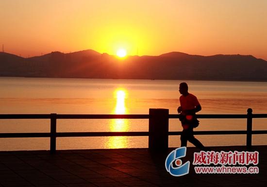 12月6日,一市民迎着朝阳在海上公园跑步健身. 威海晚报记者 姚威 摄