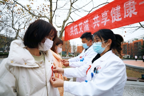校医院大夫为青年学子佩戴红丝带，希望他们提高自我防护意识，携手防艾抗艾