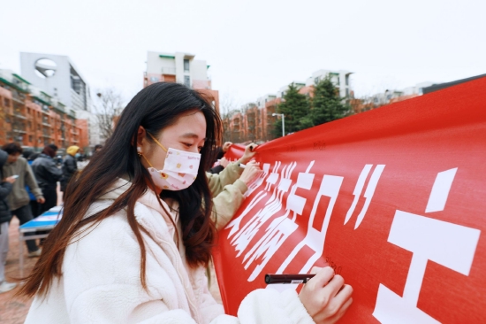 青年学子在“世界艾滋病日”主题宣传教育活动的横幅上签名，以示共抗艾滋，共享健康