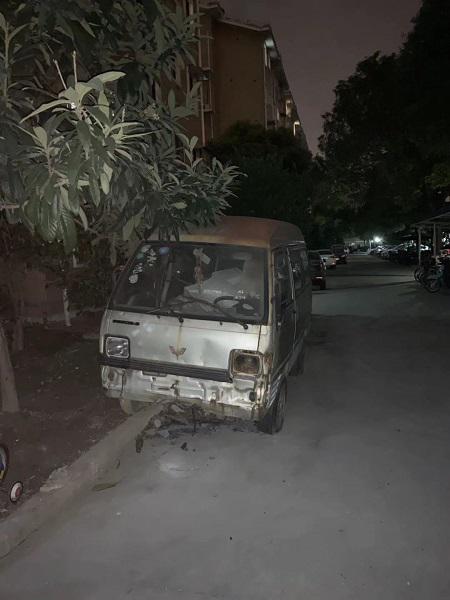 图说:白色"僵尸面包车"一侧车轮在马路,一侧在绿化带上