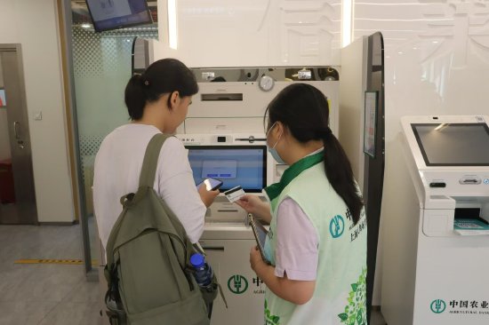 图为大学新生在农行上海五角场复旦支行工作人员的协助下，成功办理了联名卡。