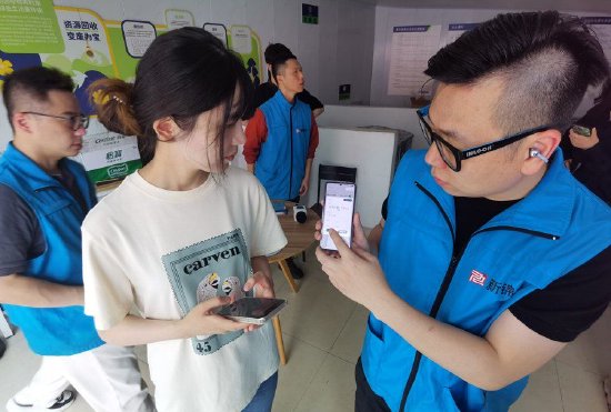 长虹小区沪尚回收惠民服务点工作人员向居民展示碳减排量。 陈玺撼摄