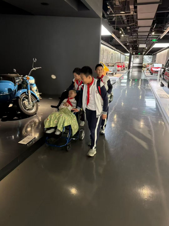 同学们推着维洛在博物馆参观，妈妈张英称这是维洛的“三大护法”。