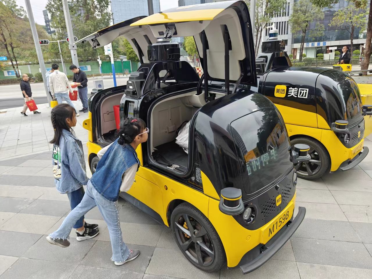 美团自动配送车开启公开道路测试当日,当地好奇市民围观。 摄影:周雄