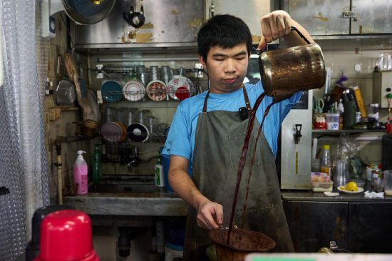 营地街市“强记奶茶咖啡”店主卫文在制作瓦煲咖啡