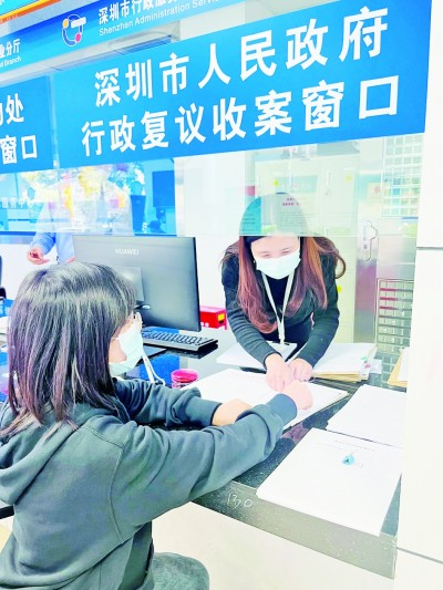 深圳市公共法律服务中心的行政复议收案窗口，工作人员正指导当事人填写表格。资料图片