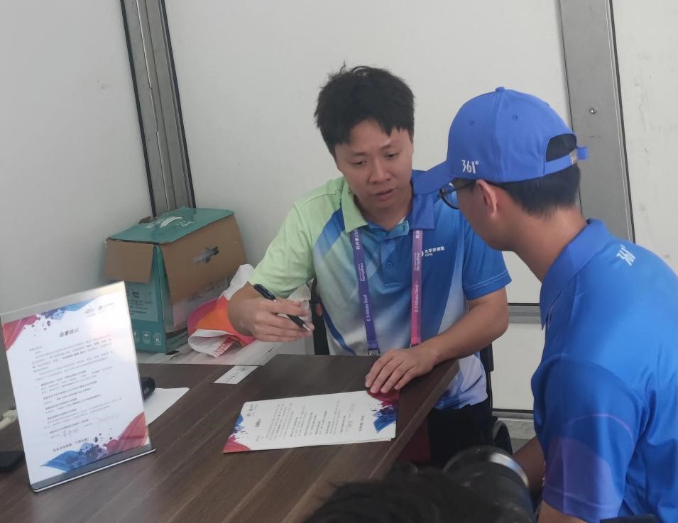 黄伟坚(左1)给志愿者介绍太保亚运保险服务