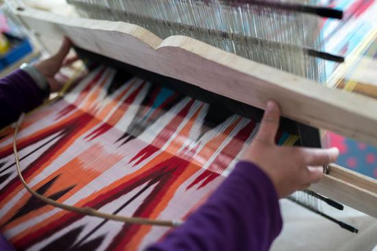 (图说:当地手艺人制作艾德莱斯丝绸的工序之一"织布")
