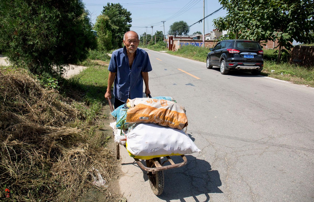 图为一位老人推着几袋落果去销售.
