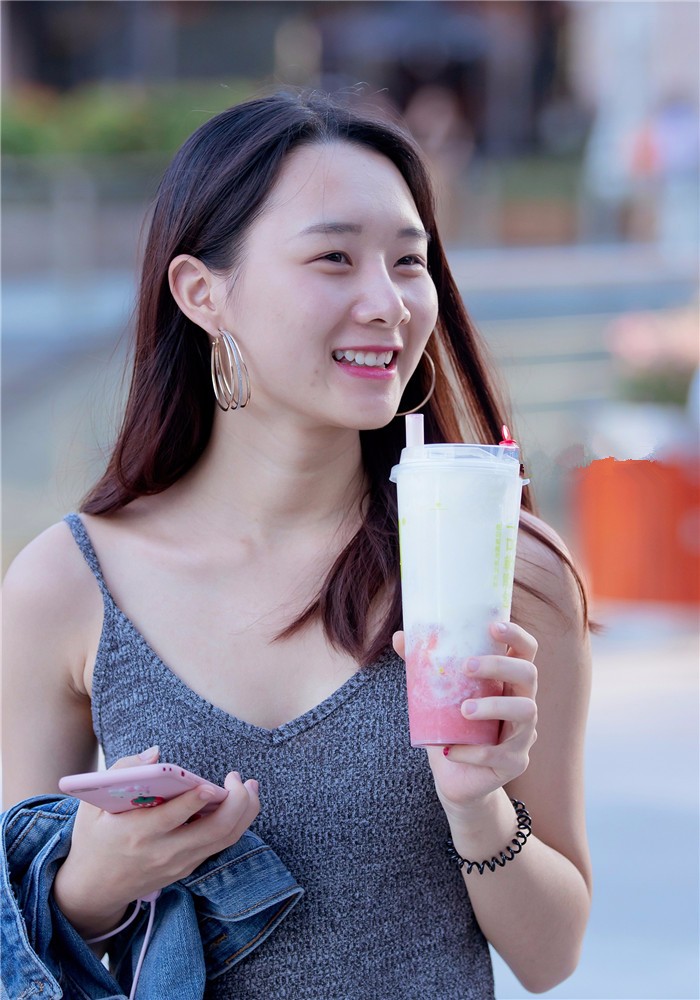 街拍美女,喝着奶茶的吊带裙女生,身材性感笑容迷人