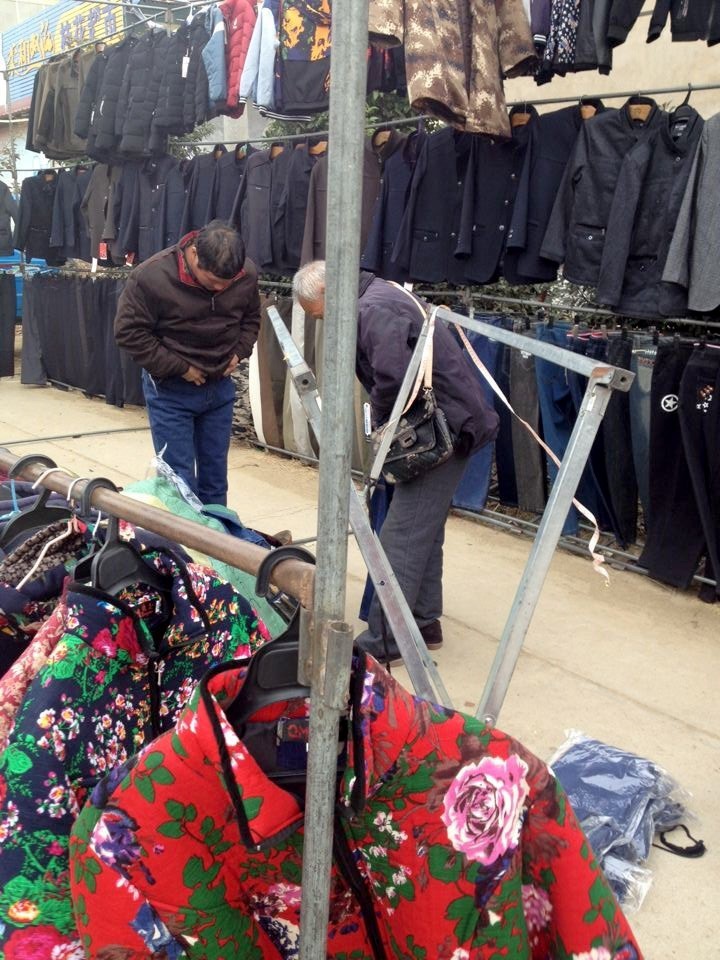 集市上,经营服装生意的最少有六七十个摊位,但几乎无人问津,赶集的人