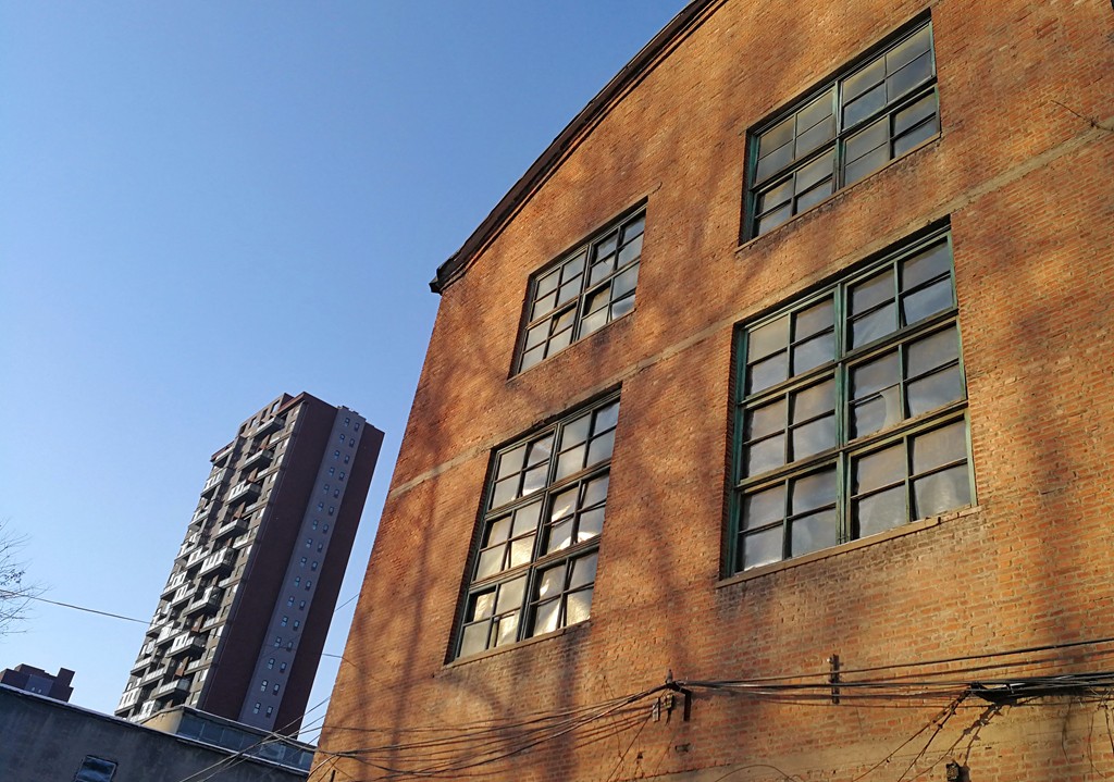 老旧的厂房和远处崭新的楼房彰显着岁月的变迁.