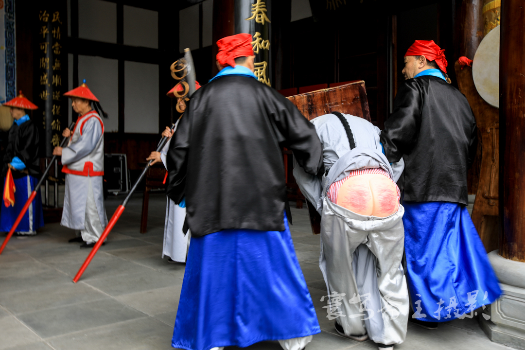 板子打完了,那两个装着假肚子的壮汉将"不孝子"抓起来,给大家看他被打