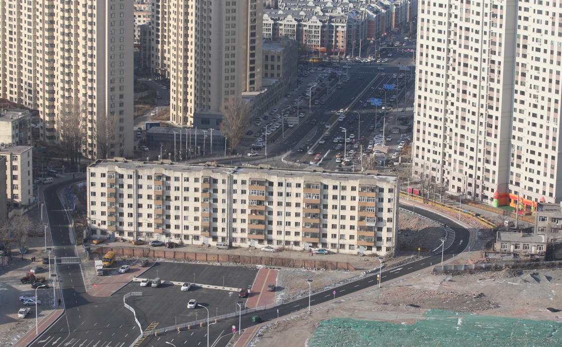 哈尔滨市哈西新区的和谐大道,一栋住房楼横跨在原定的道路中间,整栋楼