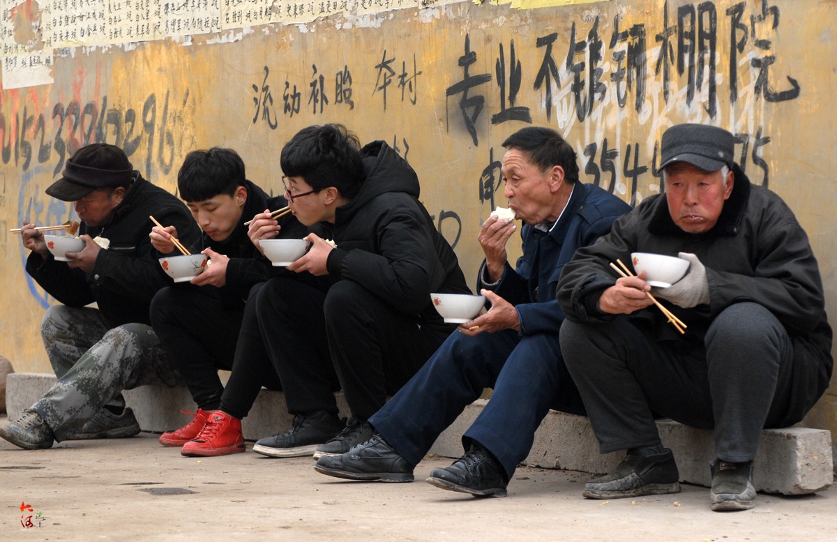 图为几名演出完还没有卸妆的年轻女子在站着吃饭.