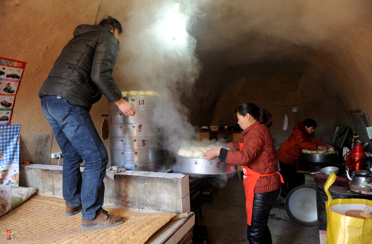 经过50分钟的大火蒸制,年馍熟了,熊占彪站到炕上将馍一笼屉一笼屉地卸