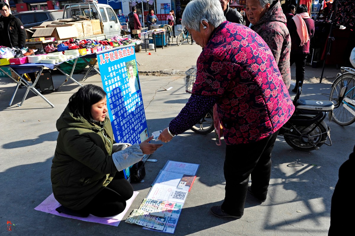 女子农村集市当街跪地为病儿乞讨,一把夺过身份证拒绝拍照
