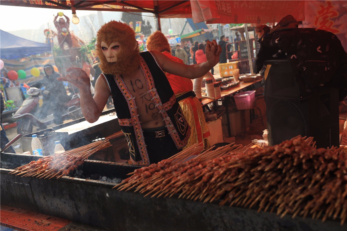 武功县武功镇一年一度的河滩会上,一家卖烤肉的摊点上,一位扮做孙悟空