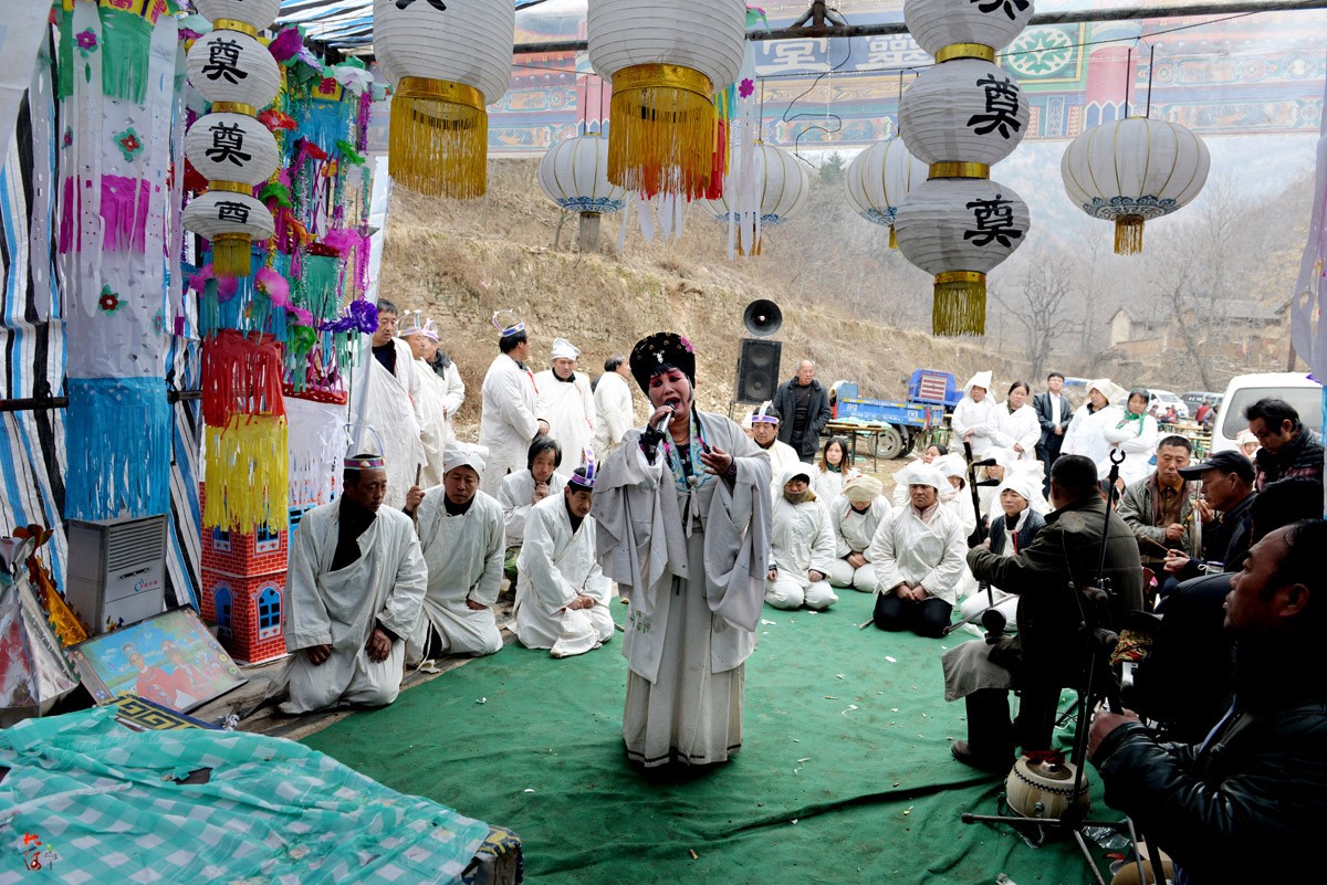 3月15日,山西乡宁,一名从事哭灵职业的妇女手拿话筒在一位去世的老人