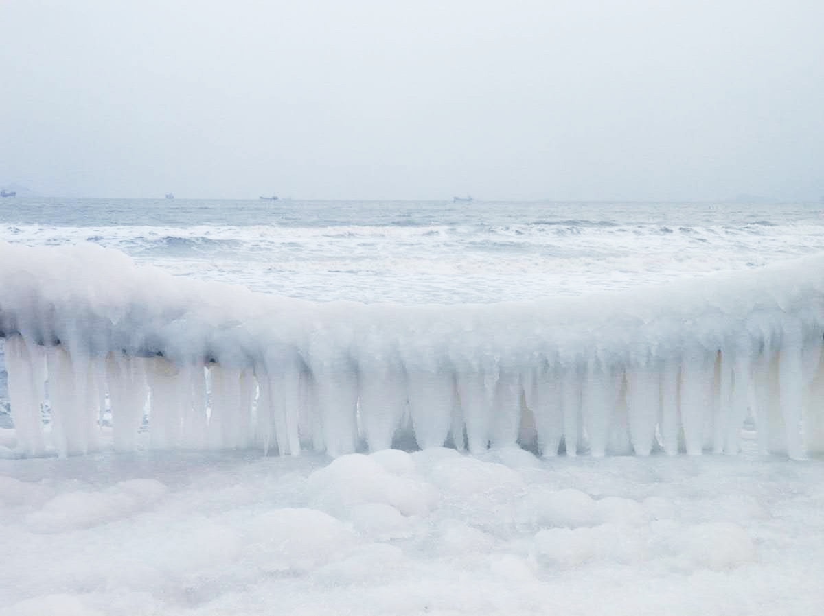 在烟台第一海水浴场附近的岸边,海水与栏杆结冰冻在一起