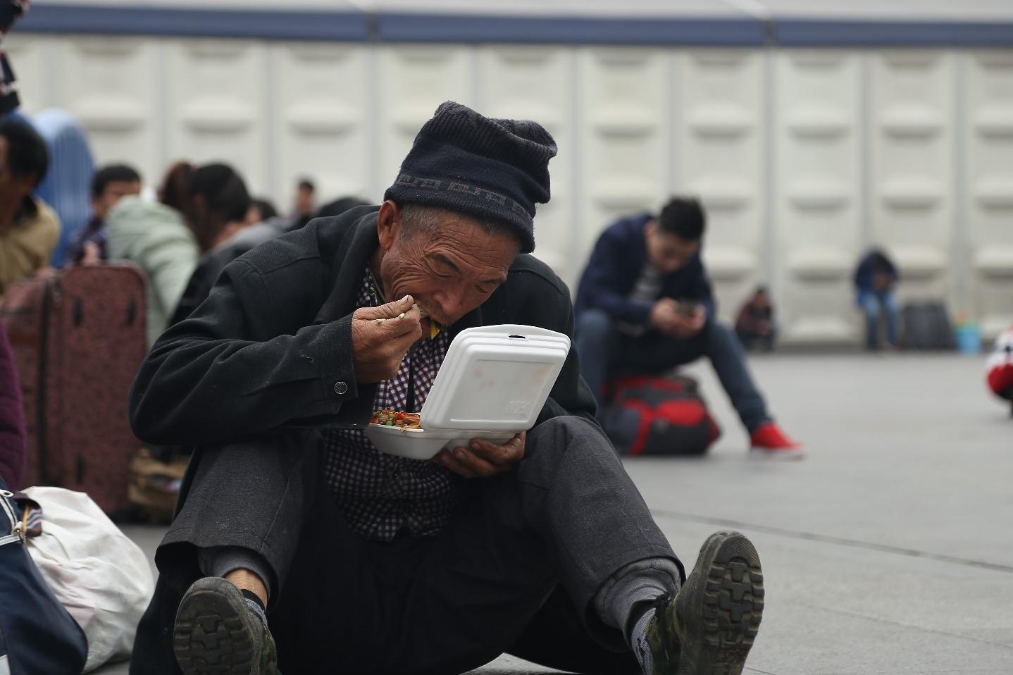 年轻乞讨者向白发老人乞讨 坐在地上吃盒饭的老人才是重点