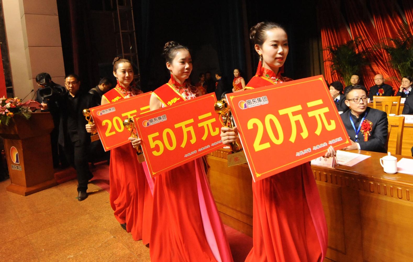 企业受表彰员工依次上台领奖,企业负责人把10万,20万,50万不等的现金