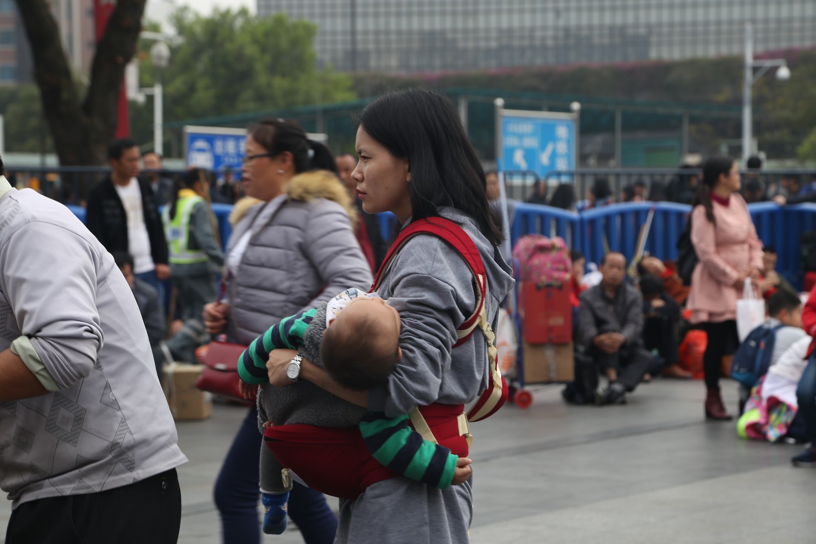 春运的气氛开始了,镜头下的这位妈妈抱着孩子睡着了.