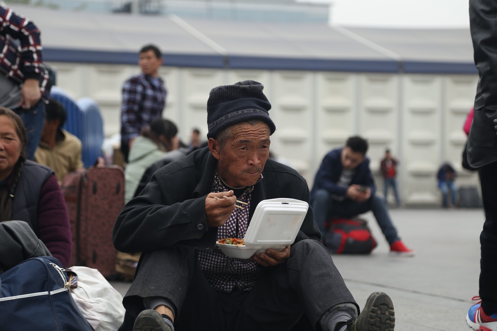年轻乞讨者向白发老人乞讨坐在地上吃盒饭的老人才是重点