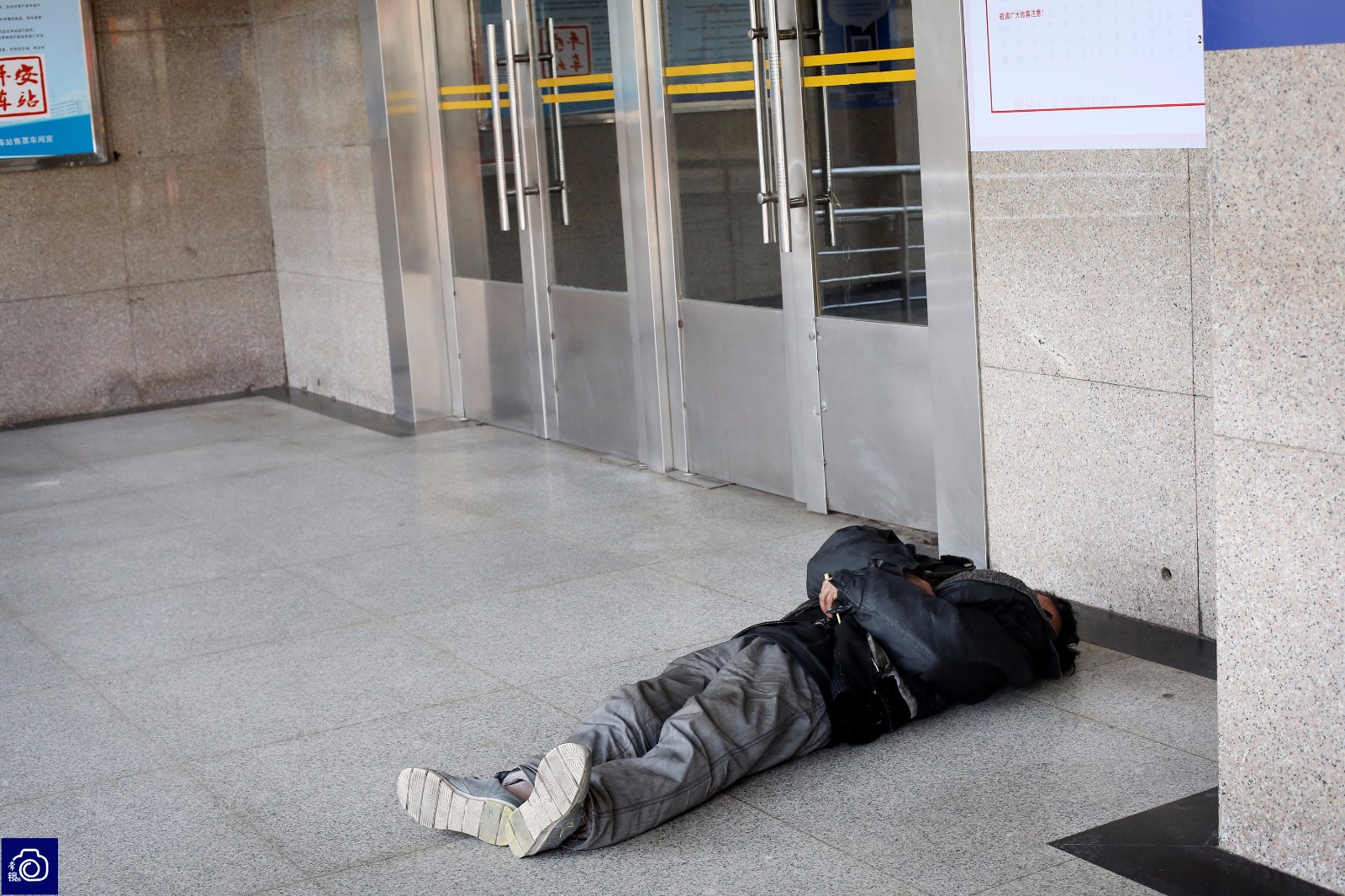 候车厅附近,一名男子因太过疲惫,直接躺在冰凉的地面上熟睡.