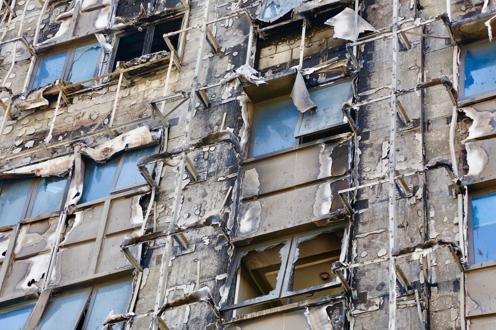 20多层高楼外墙被大火烧毁 挂巨型塑料布"遮羞"