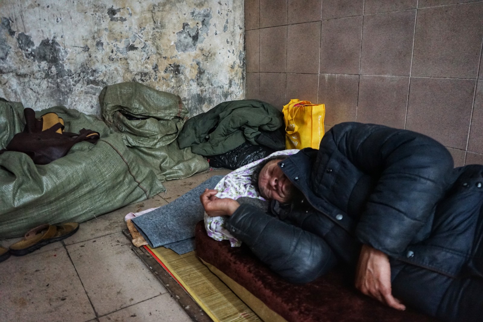 流浪汉怕冷扎堆睡地下商场 相互之间很少交谈