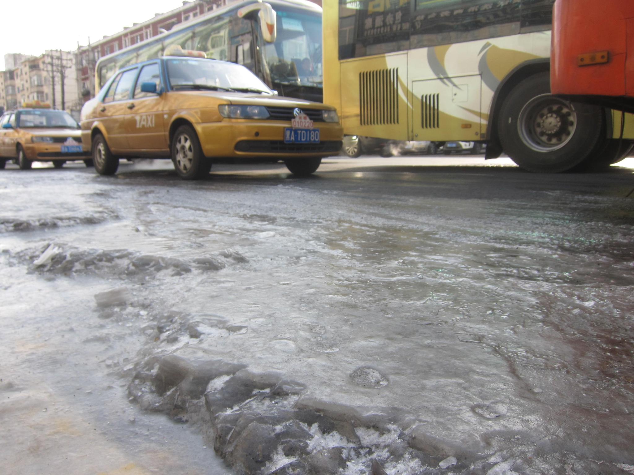 路面跑水冻冰,人车难行,多台车的轮胎被冻在冰层中