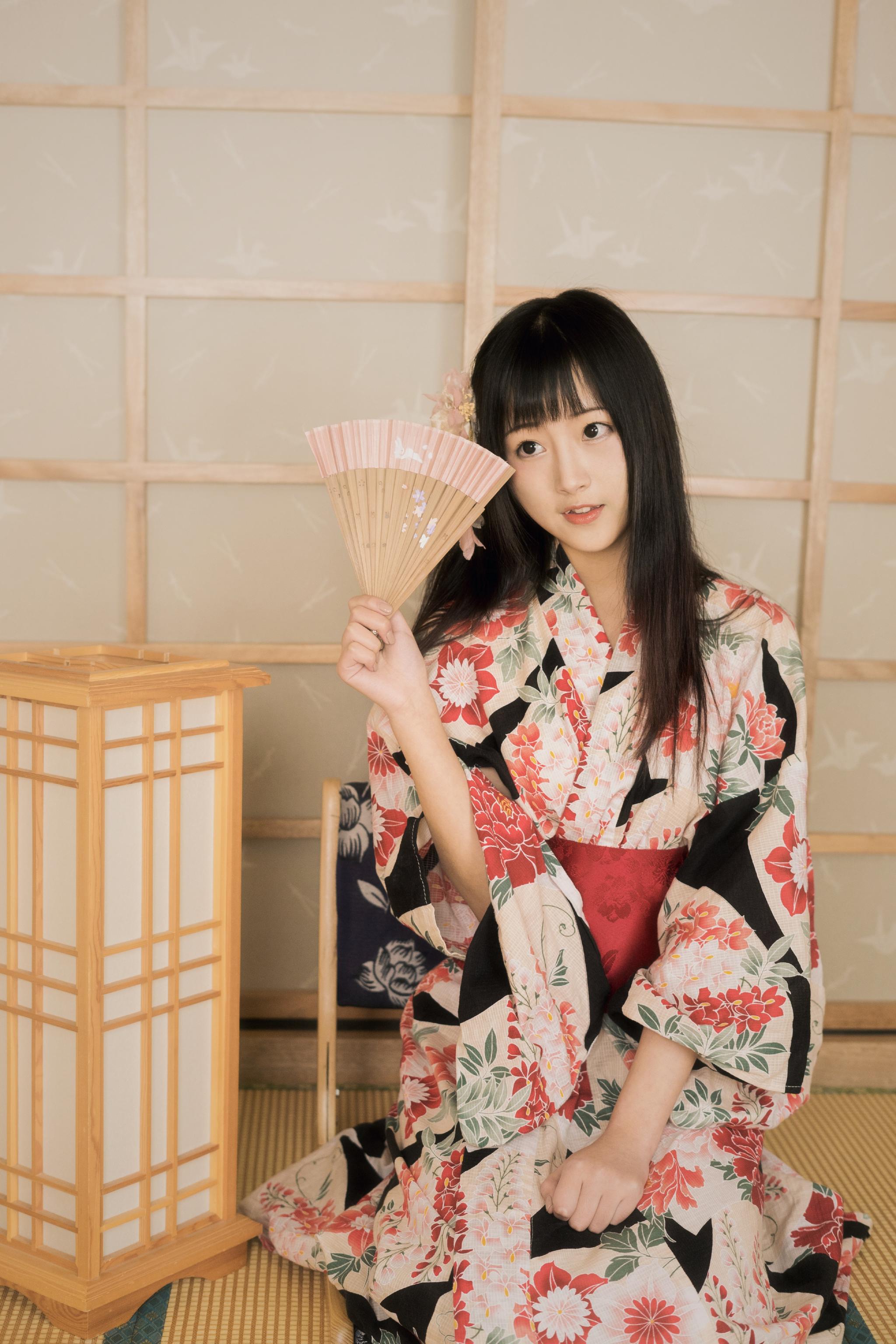 她身穿着花色的和服缠腰的布带后面一个方形的包包