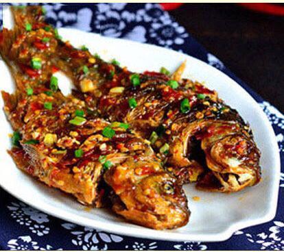 平底锅下油8成热油温,下小鲫鱼煎至两面金黄转小火,加入备好的葱姜煎