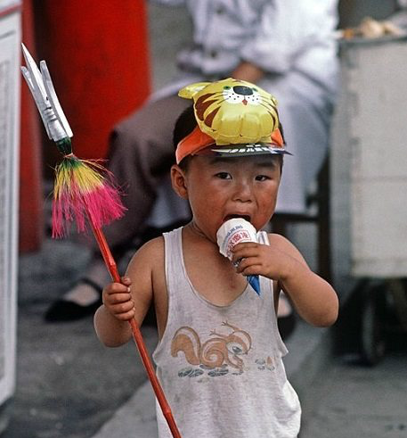 90年代,一个三四岁的小孩子站在大街上,右手拿着一支玩具方天画戟